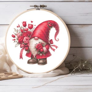 May include: A red gnome holding a bouquet of red roses and wearing a red hat with a white beard. The gnome is standing on a white background.