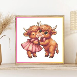 May include: A square framed cross-stitch pattern featuring two brown Highland cows with horns. The cow on the left wears a pink dress and a flower, while the cow on the right wears a pink bow tie. They are touching noses in a sweet, affectionate pose.