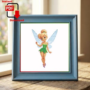 May include: A cross-stitch pattern featuring a blonde fairy with a green dress and translucent blue wings, displayed in a blue frame. The image includes the text Instant PDF Download with a red arrow icon pointing to the PDF document symbol.