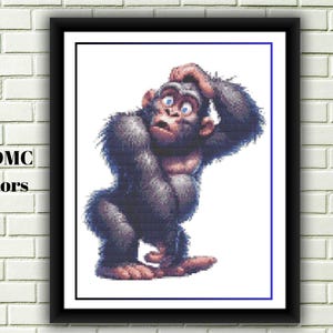 May include: A framed cross-stitch pattern featuring a cartoon gorilla with a surprised expression, hand on head. The image is in a black frame with a white border, set against a white background. The text "19 DMC Colors" is in the lower left corner.
