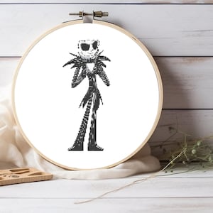 May include: Black and white cross-stitch pattern of Jack Skellington from The Nightmare Before Christmas, displayed in a round embroidery hoop.