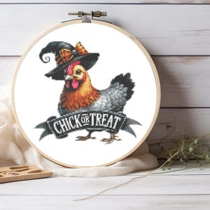 May include: A cross-stitch design of a chicken wearing a witch hat, with the words "CHICK OR TREAT" on a banner. The chicken has orange, gray, and red coloring. The design is set in a wooden embroidery hoop.