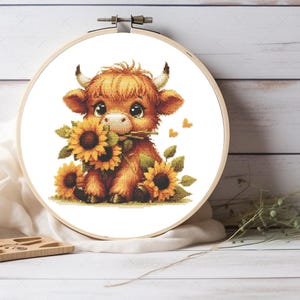 May include: A brown and white Highland cow calf with big eyes holds a bouquet of yellow sunflowers. The calf is sitting on a white background with three small orange hearts.