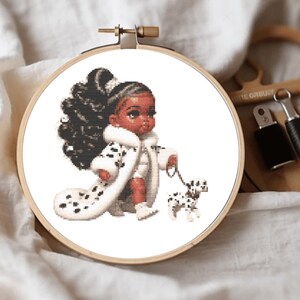 May include: A cross-stitch pattern in a wooden embroidery hoop featuring a dark-skinned character with a high ponytail wearing a white coat with black spots, holding a leash attached to a small white and black spotted puppy on a white background.