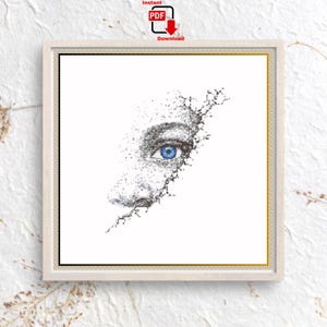 May include: A cross stitch pattern featuring a black and white pixelated design of a human eye with a vibrant blue iris. The image is framed within a square border and includes the text Instant PDF Download at the top of the composition.