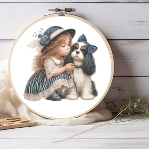 May include: A cross-stitch embroidery project in a round wooden hoop featuring a young child with long hair wearing a blue hat and a striped dress, leaning toward a black and white dog with a blue bow on its head, all rendered in detailed stitches.