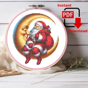 May include: A cross-stitch embroidery hoop featuring Santa Claus seated on a crescent moon. Santa is dressed in a red suit and hat, with a white beard and a red sack. The moon is a golden yellow color. The text "Instant PDF Download" is also visible.
