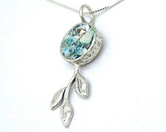 May include: A silver pendant necklace featuring an oval-shaped, mosaic-like stone in shades of blue and white. The pendant is accented with a textured silver setting and a stylized leaf design. The necklace chain is also silver.