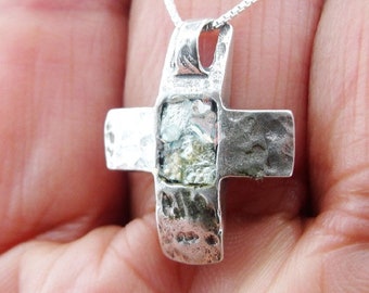 May include: Silver cross pendant with a hammered texture and a clear glass center piece. The pendant is on a silver chain.