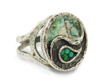 May include: A silver ring with a yin yang design. One side of the ring is made of green and white mosaic glass, and the other side is black with green opal stones.