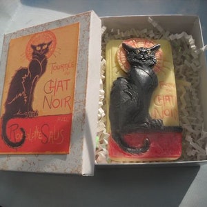 Op de afbeelding: Een zwarte kat op een witte achtergrond met de tekst "Tournée du Chat Noir avec  Rodolphe Salis" in een rood en geel kader. De kat zit op een rode en gele achtergrond met de tekst "Chat Noir" in een wit kader.