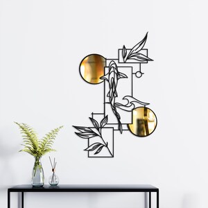 May include: Black metal wall art featuring a koi fish design with gold accents. The artwork includes geometric shapes, leaves, and two gold circles. The koi fish is swimming through the design, creating a modern and artistic look.