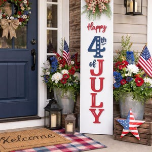 May include: A patriotic front porch scene with a blue door, wreath, and a welcome mat. A vertical sign reads "Happy 4th of July" with red and blue lettering. Galvanized buckets hold floral arrangements and American flags.