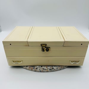 May include: A set of three ceramic mugs with a speckled, matte finish. The mugs are in shades of cream, light brown, and dark brown. Each mug has a simple, minimalist design and a rounded handle. The mugs are likely for coffee or tea.