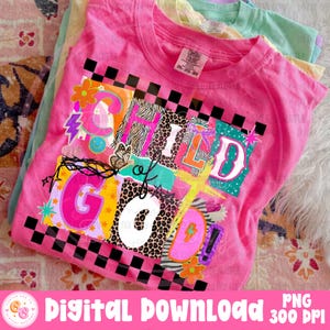 May include: A pink t-shirt with the words "CHILD of GOD" in a colorful, patchwork design. The design includes floral and lightning bolt graphics, a butterfly, and a black and white checkered border. The shirt is folded with other pastel-colored shirts.