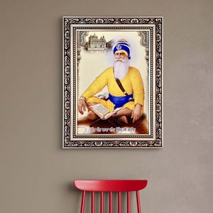 May include: A framed portrait of a religious figure in yellow and blue attire, seated and holding a book. The portrait has a decorative border and is hanging on a neutral-colored wall above a red chair with an open book.