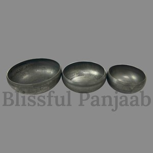 May include: Three metal bowls of varying sizes are arranged in a row. The bowls have a dark, metallic finish and a rounded shape. The text "Blissful Panjaab" is at the bottom of the image.