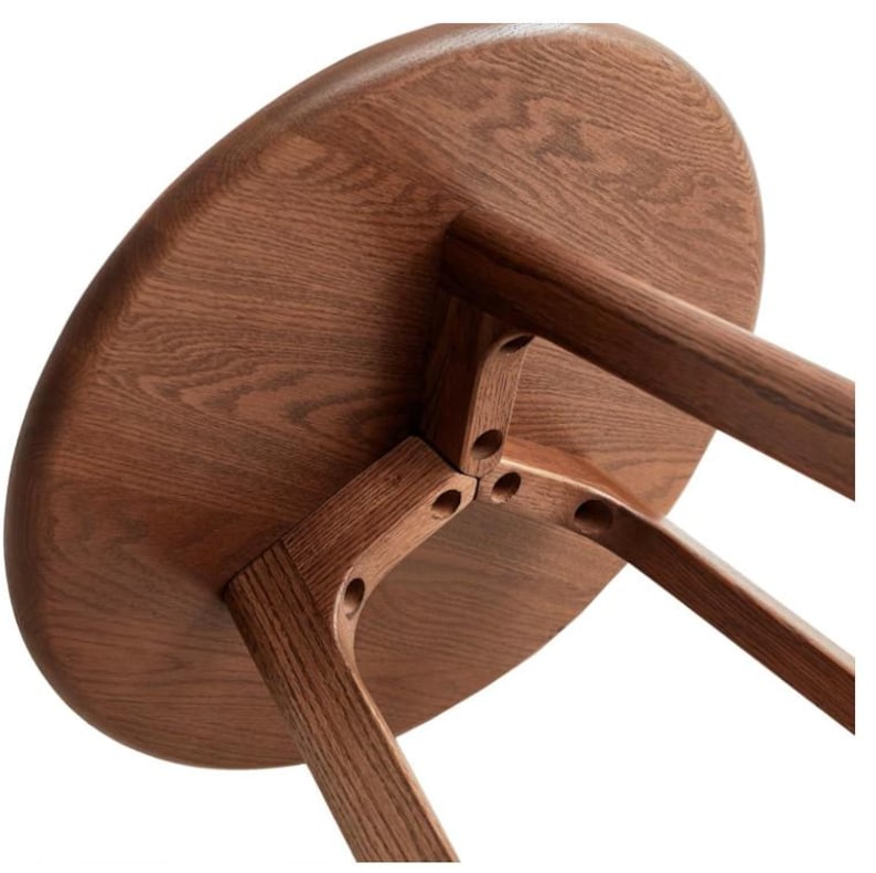 Puede incluir: Una mesa redonda de madera con un patr&oacute;n de veta visible, que presenta tres patas resistentes conectadas a la parte inferior del tablero con detalles de uni&oacute;n circulares. La pieza est&aacute; construida en madera de tono marr&oacute;n medio con acabado liso.