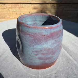 May include: A ceramic vase with a blue and red glaze. The vase has a rounded shape and a wide opening.