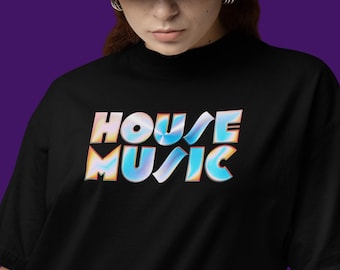 Puede incluir: Camiseta negra con la frase "HOUSE MUSIC" en una fuente iridiscente y colorida. La persona lleva un sombrero de pescador azul. El texto está en negrita y estilizado.