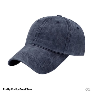Può includere: Un berretto da baseball in cotone blu scuro lavato. Il berretto ha una visiera curva e una corona strutturata.