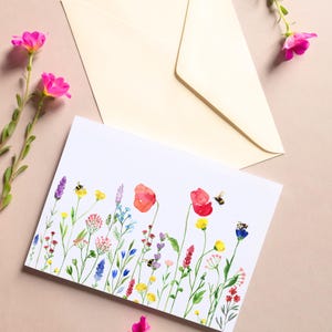 Puede incluir: Una ilustración de acuarela de un campo de flores silvestres con abejas. Las flores son en tonos de rosa, rojo, amarillo, azul y verde. Las abejas son negras y amarillas.