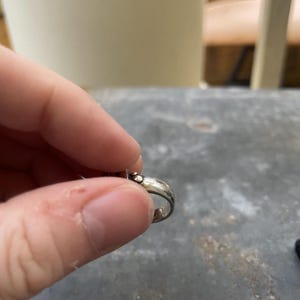 Puede incluir: Una taza de cer&aacute;mica blanca con un asa negra y el texto "But First, Coffee" en negrita negra. La taza se encuentra sobre un fondo borroso, sugiriendo un ambiente acogedor.