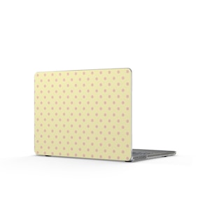 May include: A laptop computer featuring a pale yellow exterior shell decorated with a repeating pattern of small, light pink polka dots. The device is shown from a rear-facing angle, displaying the lid and the side profile of the base unit.