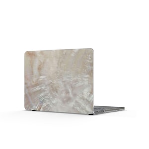 May include: A laptop computer featuring a protective hard shell case with a glossy, iridescent mother-of-pearl finish. The surface displays swirling patterns of cream, beige, and soft white tones with a reflective, pearlescent texture.