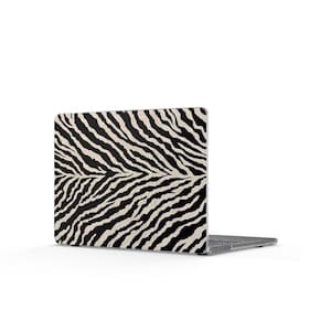 May include: A laptop computer featuring a protective skin or cover with a high-contrast black and white zebra stripe pattern. The design covers the entire outer lid of the device, displaying a repeating organic animal print across the surface.