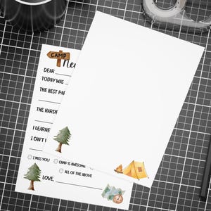 May include: A printable letter writing template with a camp theme. The template has a handwritten title "Camp News" and includes a list of prompts for writing a letter, such as "Dear", "Today was", "The best part", "The hardest part", "I learned", "I can't wait to", "I miss you", "Camp is awesome", "All of the above", and "Love". The template also includes illustrations of a pine tree, a tent, and a compass.