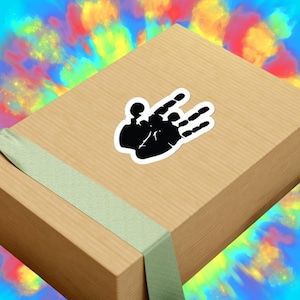 May include: A brown gift box with a green ribbon. A black handprint sticker is on the box. The handprint is a popular symbol of the Grateful Dead.