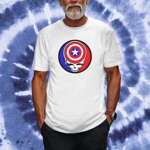 Puede incluir: Camiseta blanca con un gr&aacute;fico rojo, blanco y azul de una calavera con un escudo de Capit&aacute;n Am&eacute;rica en la parte superior.