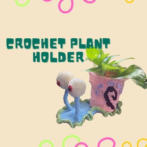 Puede incluir: Un original soporte para plantas de ganchillo con diseño de caracol, con grandes ojos saltones y una maceta en forma de concha. La maceta es rosa y contiene una planta verde. El texto "CROCHET PLANT HOLDER" está arriba.