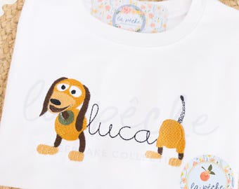Camisa de juguete personalizada, camisa bordada de perro Slink para estudios, nombre personalizado para Magical Vacation Studios, camisa para niños, camisa para el primer viaje