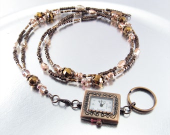 May include: A brown and gold beaded necklace with a square watch attached. The watch has a white face with black numbers and hands. The necklace has a key ring attached.