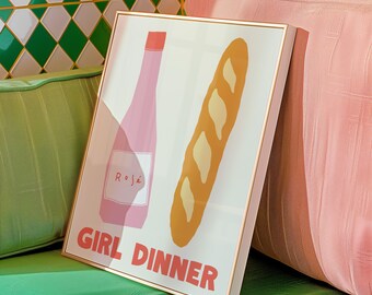 Könnte beinhalten: Ein weißer gerahmter Druck mit einer rosafarbenen Flasche Roséwein und einem Baguette auf weißem Hintergrund. Der Text "GIRL DINNER" ist in roten Buchstaben unten auf dem Druck geschrieben.