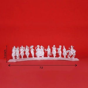 May include: A silver-colored religious figurine set featuring multiple figures, including deities and a rider on horseback. The figures are arranged on a curved base, with a total length of 7.2 inches and a height of 1.6 inches.