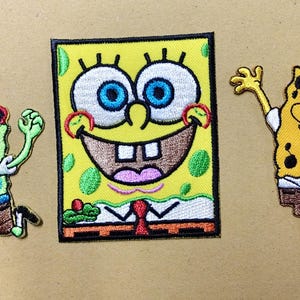 Op de afbeelding: Drie geborduurde patches met het personage SpongeBob SquarePants. Eén patch toont het personage als piraat met een zwaard, één is een rechthoekig portret en één toont het personage dat zwaait met beide armen omhoog.