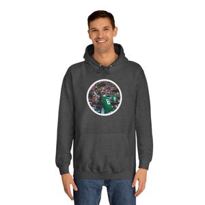May include: A dark grey hooded sweatshirt with a white circle graphic featuring a football player in a green and white uniform celebrating a touchdown in front of a crowd.