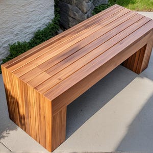 May include: A wooden bench with a natural finish. The bench is made of slats of wood and has a simple, modern design.