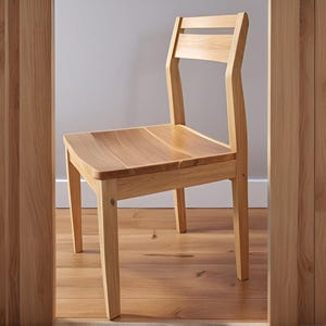 Puede incluir: Una silla de madera de color claro con respaldo de listones y asiento contorneado. La silla tiene cuatro patas rectas y está hecha de madera de color claro. La silla está colocada en una habitación con paneles y suelo de madera.