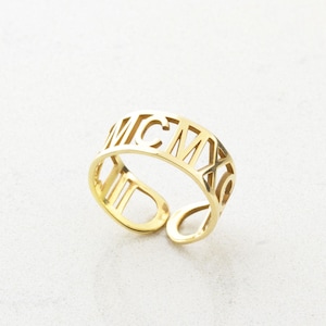 Może przedstawiać: Złoty pierścionek z wygrawerowanym na obrączce rzymskim numerem MCMXC.