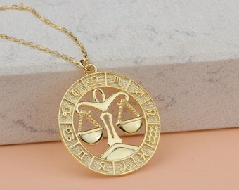 May include: Gold necklace with a round pendant featuring the zodiac symbol for Libra. The pendant is surrounded by a circle with the zodiac symbols for all twelve signs.