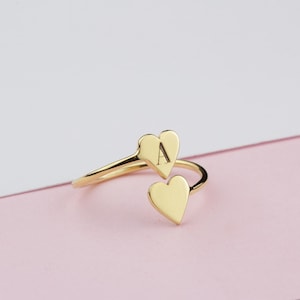 Peut inclure: Bague en or avec deux breloques en forme de cœur. Le plus grand charme a la lettre "A" gravée dessus.
