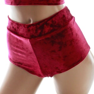 May include: A two-piece outfit in a deep burgundy velvet fabric. The top is a cropped tank top with a scoop neck. The shorts are high-waisted and have a wide leg.