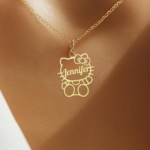 May include: A gold-colored pendant necklace featuring a cut-out design of a cartoon character with the name "Jennifer" inscribed. The pendant is suspended from a delicate chain, creating a personalized and charming accessory.