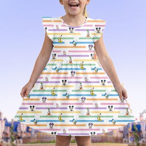 May include: A white dress with a colorful striped pattern featuring Disney characters like Mickey Mouse, Donald Duck, and Minnie Mouse. The dress has flutter sleeves and a round neckline, perfect for a young child.