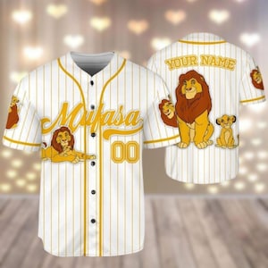 May include: White baseball jersey with gold stripes and a lion king character print. The jersey has the text "Mufasa" and the number "00" on the front. The back of the jersey has the text "YOUR NAME".