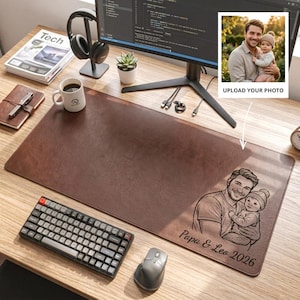 May include: A brown leather desk mat with a personalized illustration of a father and child. The mat features a keyboard, mouse, and a coffee mug. The image also includes a computer monitor, headphones, and a small plant.